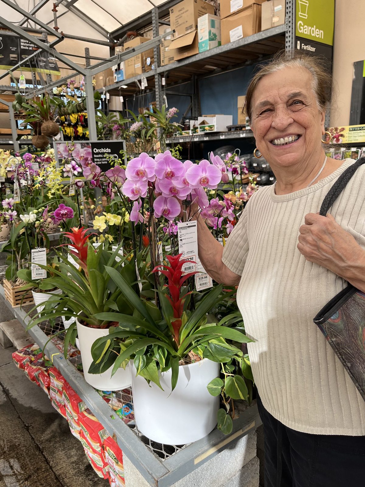 Dorina smiling beside pink orchids at the garden center